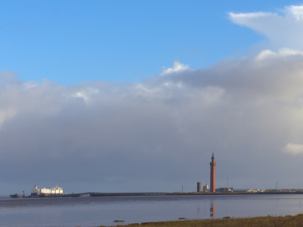 The River Humber under blue skies and cloud and with Grimsby Dock Tower in the distance
